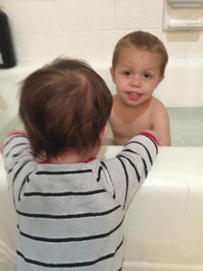 Austin practicing his standing against the bath tub while Parker takes a bath 